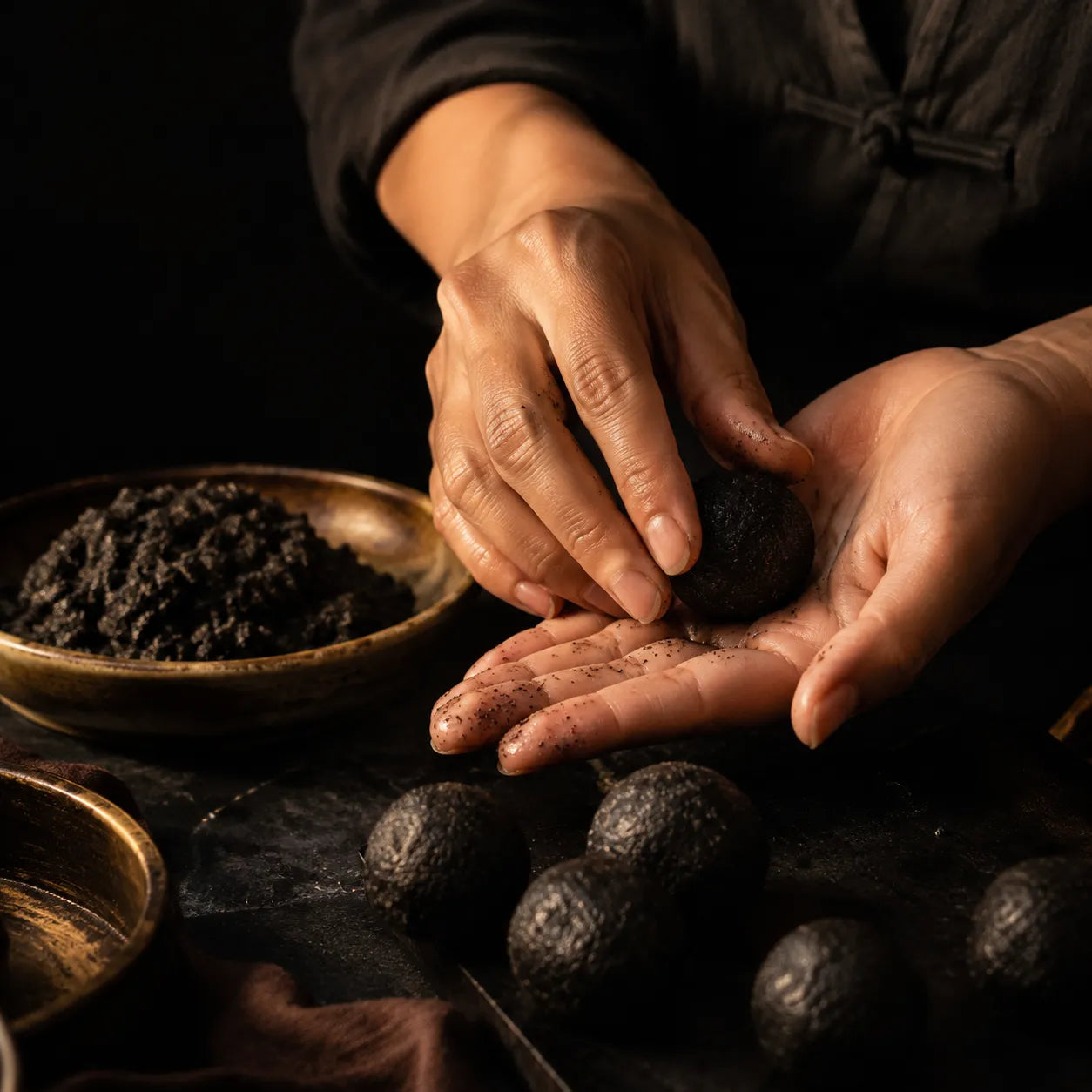 Black sesame balls being shaped by hand